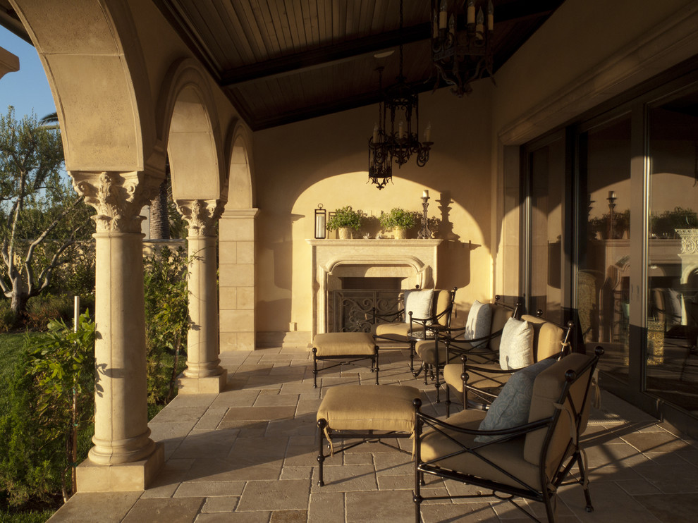 Photo of a mediterranean patio in Orange County with a fire feature and a roof extension.