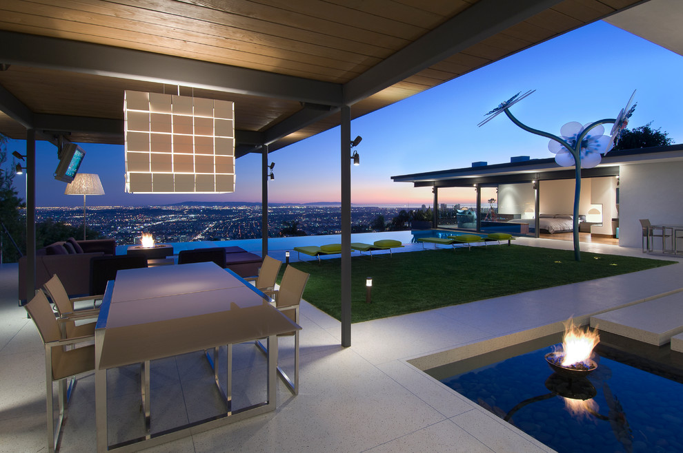 This is an example of an expansive modern back patio in Los Angeles with a fire feature, tiled flooring and a roof extension.