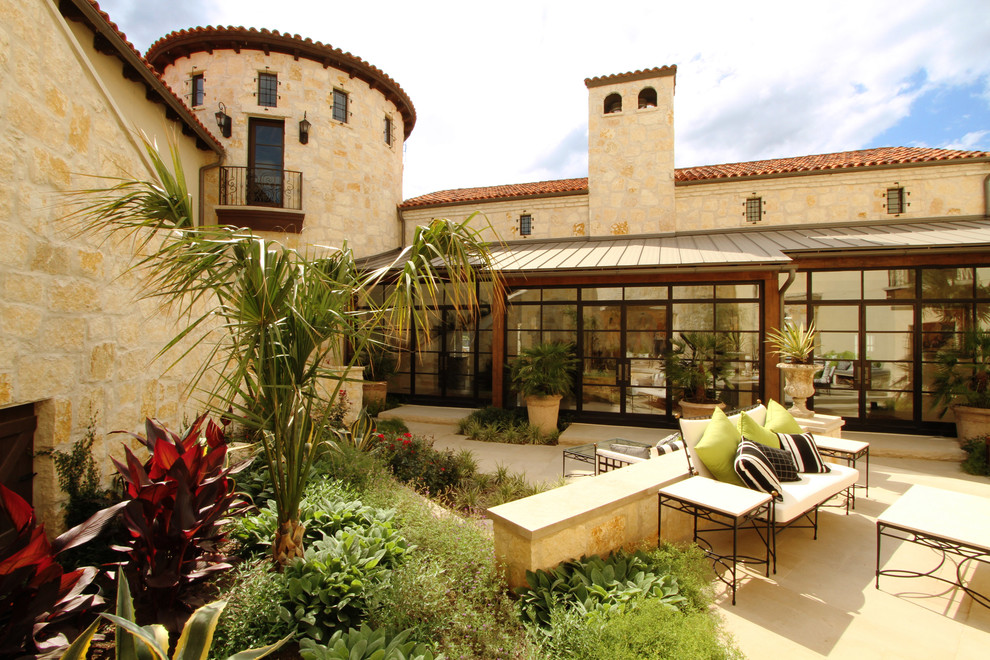 Inspiration for a large mediterranean courtyard stone patio remodel in Austin with a fire pit and no cover