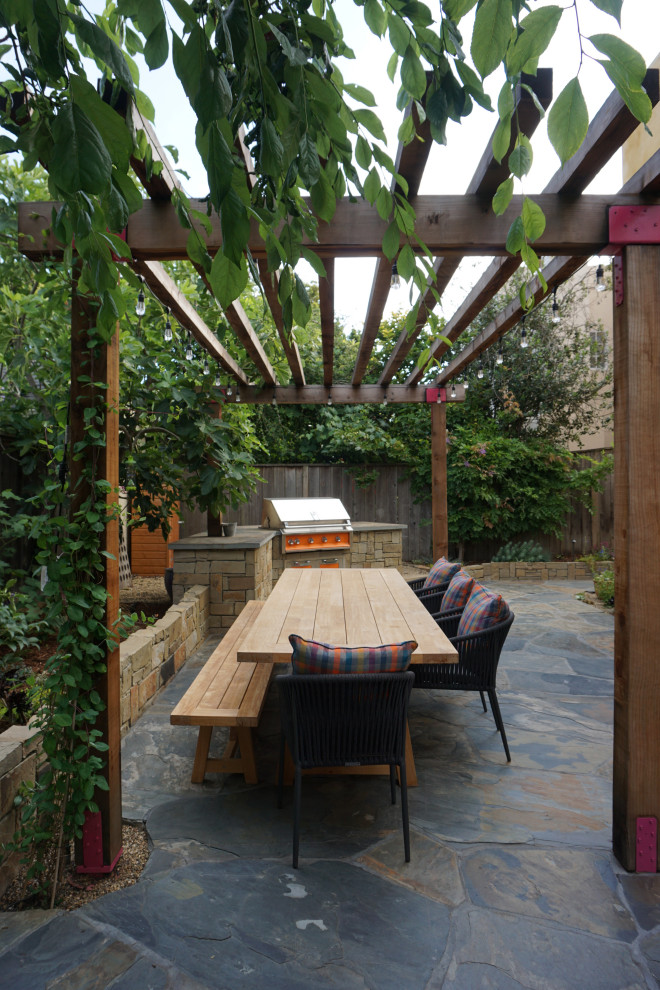Ispirazione per un patio o portico tradizionale di medie dimensioni e dietro casa con pavimentazioni in pietra naturale e una pergola