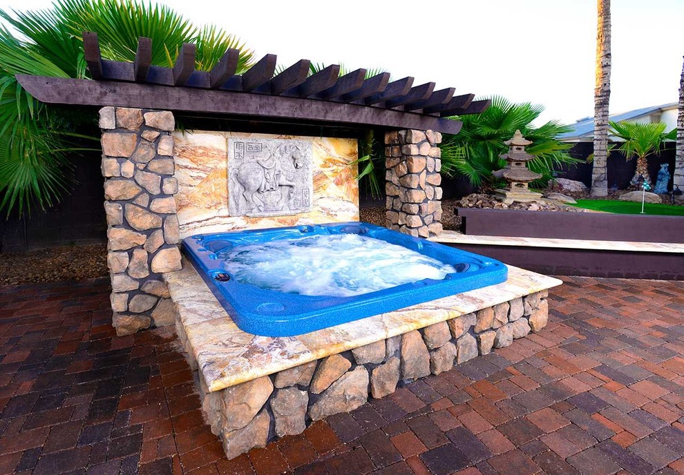 This is an example of a small world-inspired back patio in Phoenix with a water feature.
