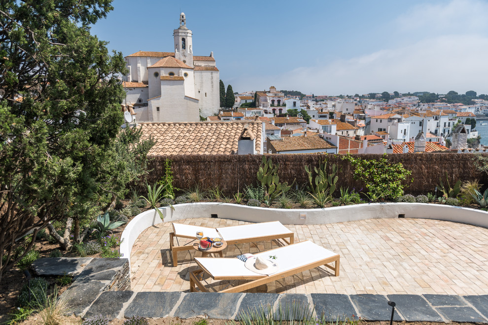 Diseño de patio mediterráneo sin cubierta en patio trasero con adoquines de ladrillo
