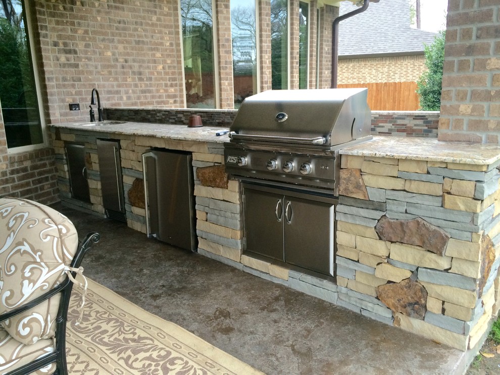 Réalisation d'une terrasse arrière design avec une cuisine d'été, du béton estampé et une extension de toiture.