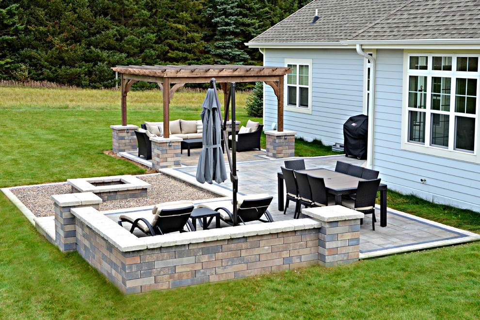 Idee per un grande patio o portico minimalista dietro casa con un focolare e pavimentazioni in mattoni