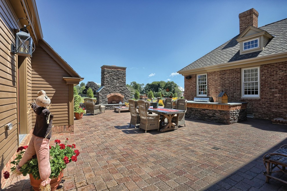 Foto di un grande patio o portico country in cortile con un focolare e pavimentazioni in mattoni