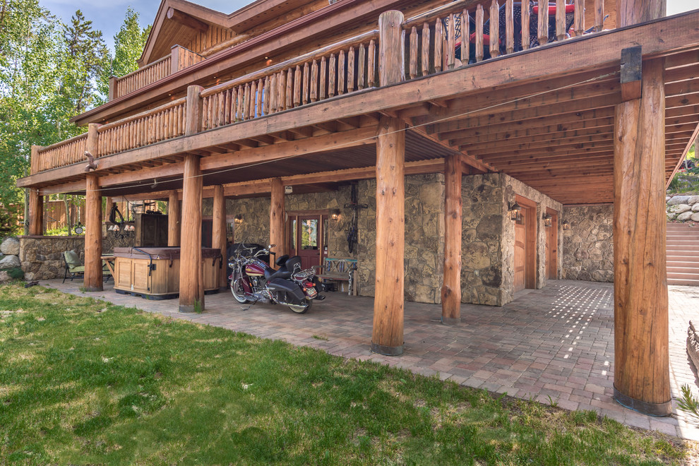 Immagine di un grande patio o portico rustico dietro casa con pavimentazioni in mattoni e un tetto a sbalzo