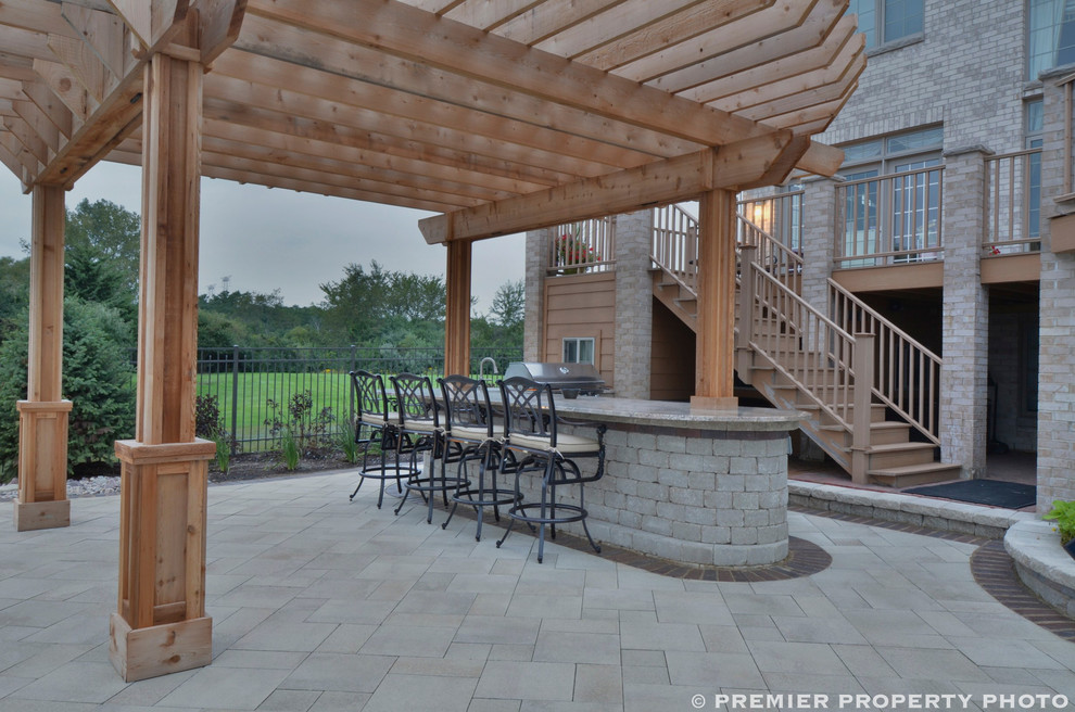 Patio kitchen - huge contemporary backyard concrete paver patio kitchen idea in Chicago with a pergola