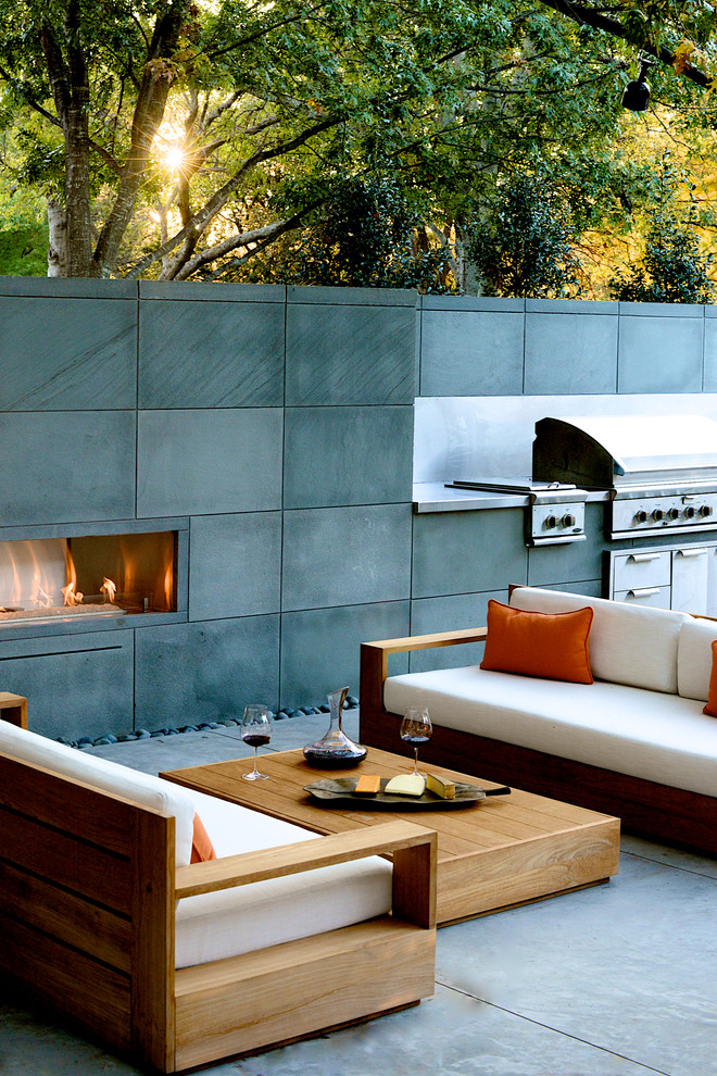 Cette image montre une terrasse arrière design de taille moyenne avec un foyer extérieur et une dalle de béton.