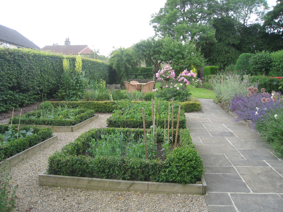 Medium sized contemporary back garden in Cheshire with a vegetable patch and natural stone paving.