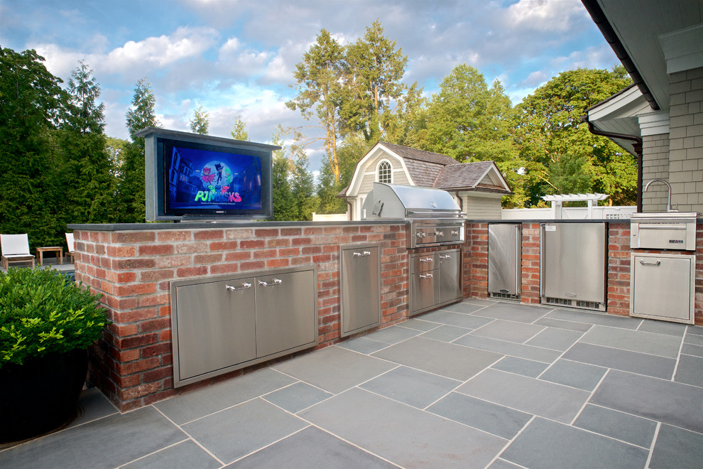 Large elegant backyard stone patio kitchen photo in New York