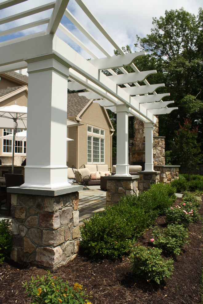 Modelo de patio clásico de tamaño medio en patio trasero con adoquines de piedra natural y pérgola