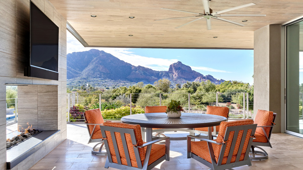 Inspiration for an expansive modern back patio in Phoenix with a fireplace, natural stone paving and a roof extension.