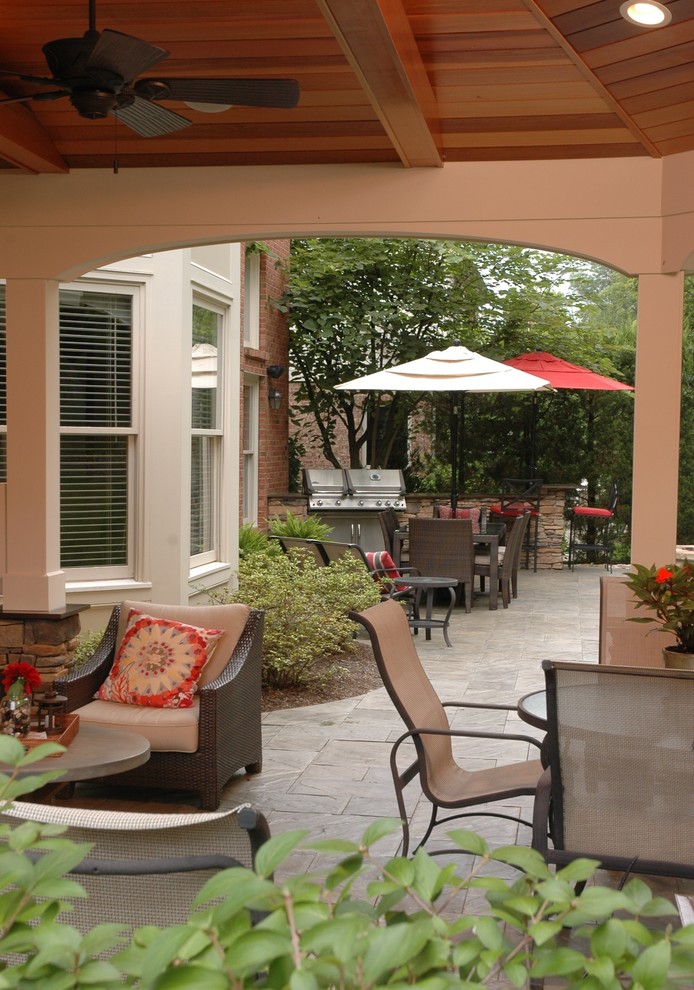 Immagine di un patio o portico classico di medie dimensioni e dietro casa con cemento stampato e un tetto a sbalzo