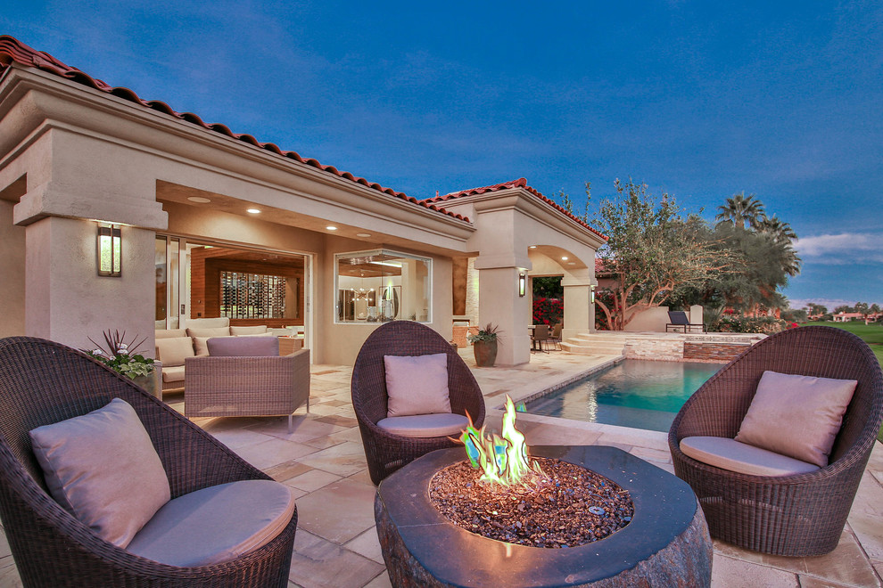 Medium sized contemporary back patio in Los Angeles with a fire feature, natural stone paving and a roof extension.