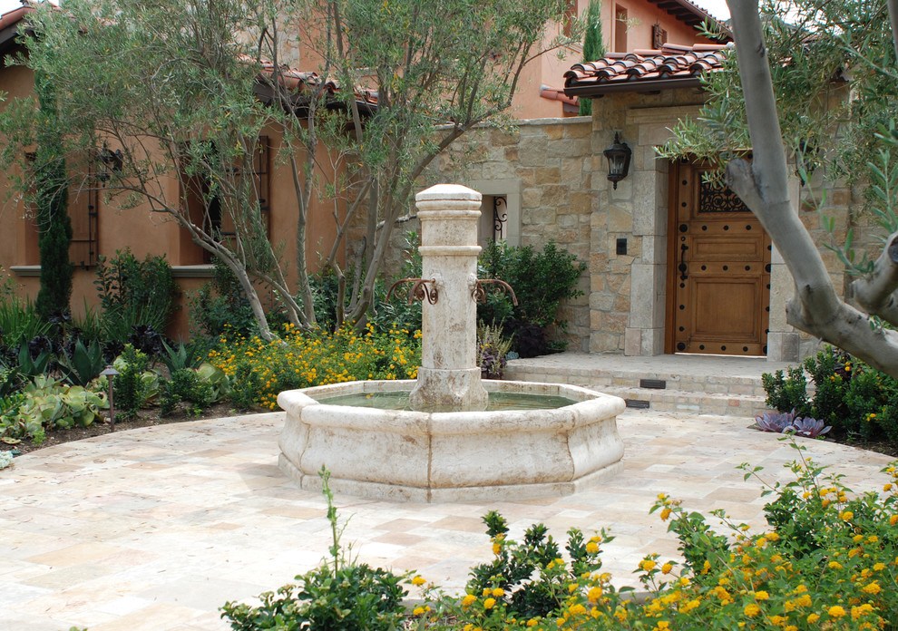 Aménagement d'une terrasse méditerranéenne de taille moyenne avec un point d'eau, une cour, des pavés en pierre naturelle et aucune couverture.