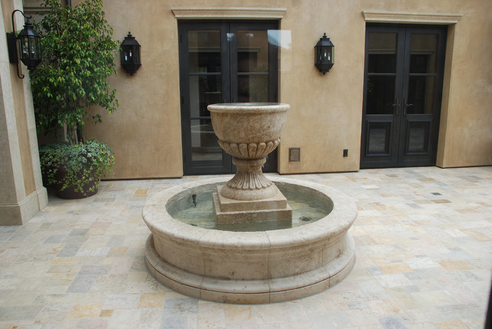 На фото: двор среднего размера на внутреннем дворе в средиземноморском стиле с покрытием из каменной брусчатки и фонтаном без защиты от солнца