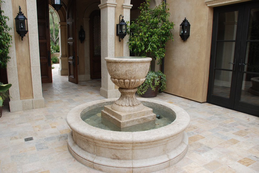 Imagen de patio mediterráneo de tamaño medio sin cubierta en patio con fuente y adoquines de piedra natural