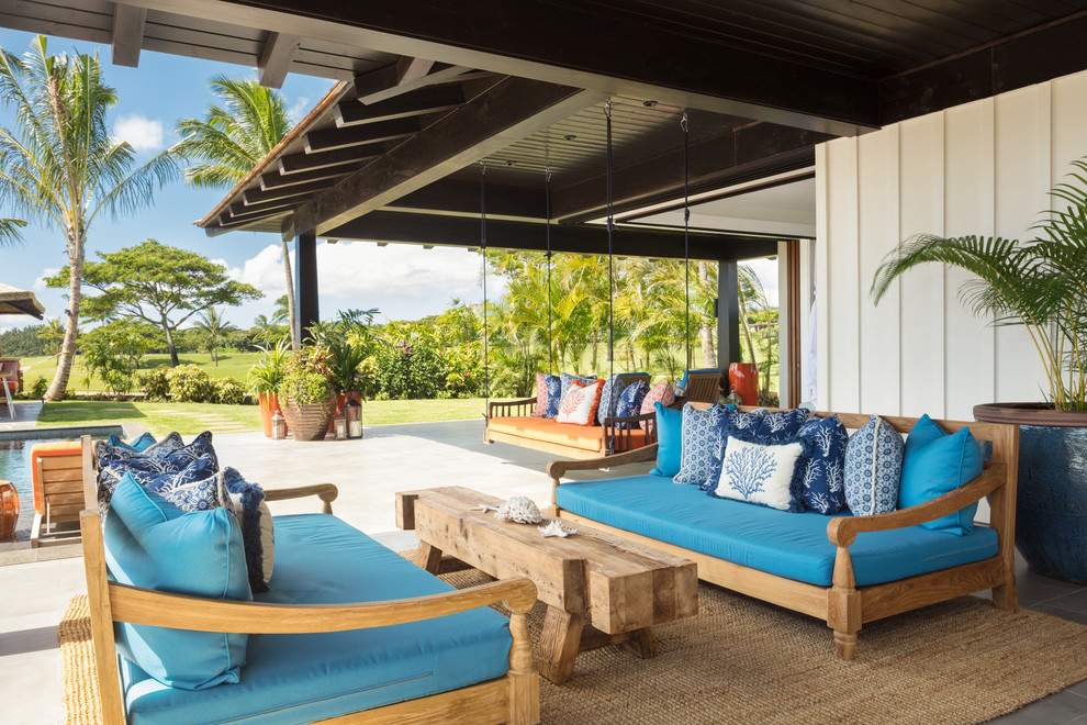 Idées déco pour une grande terrasse arrière exotique avec du carrelage et une extension de toiture.