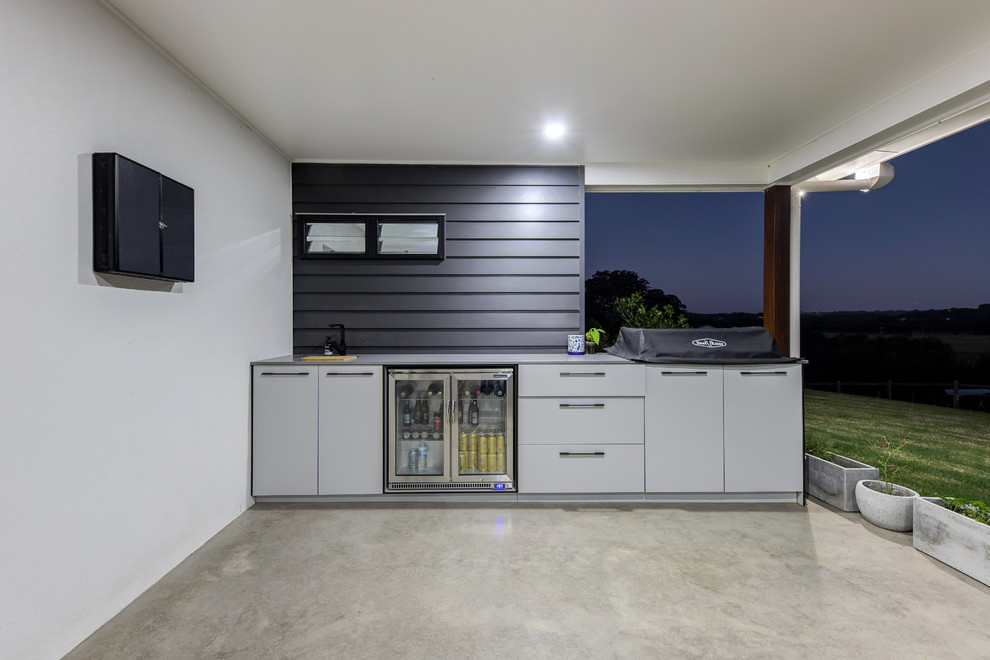 Large industrial back patio in Sunshine Coast with an outdoor kitchen, concrete slabs and a roof extension.