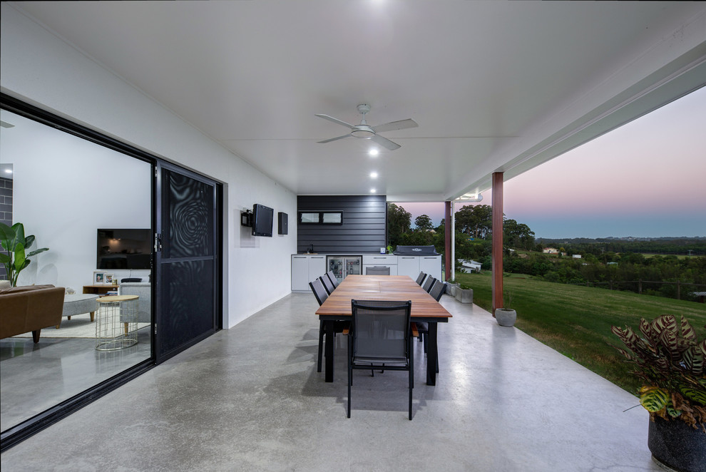 Пример оригинального дизайна: большой двор на заднем дворе в стиле лофт с летней кухней, покрытием из бетонных плит и навесом