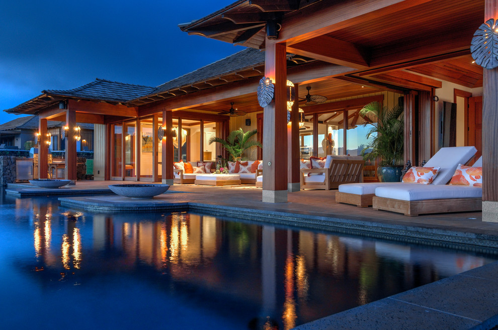 Esempio di un ampio patio o portico tropicale dietro casa con un focolare, piastrelle e un tetto a sbalzo