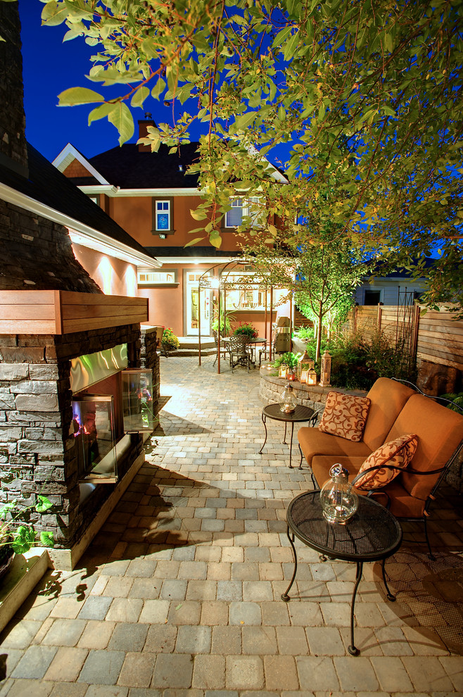 Immagine di un patio o portico chic di medie dimensioni e dietro casa con un caminetto
