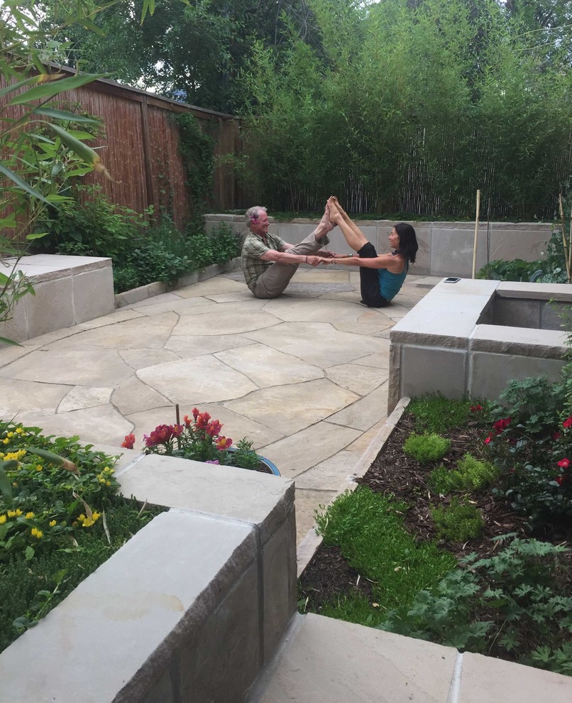 Small world-inspired back patio with natural stone paving and no cover.