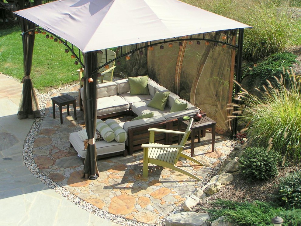 Example of a large eclectic backyard stamped concrete patio design in New York with an awning