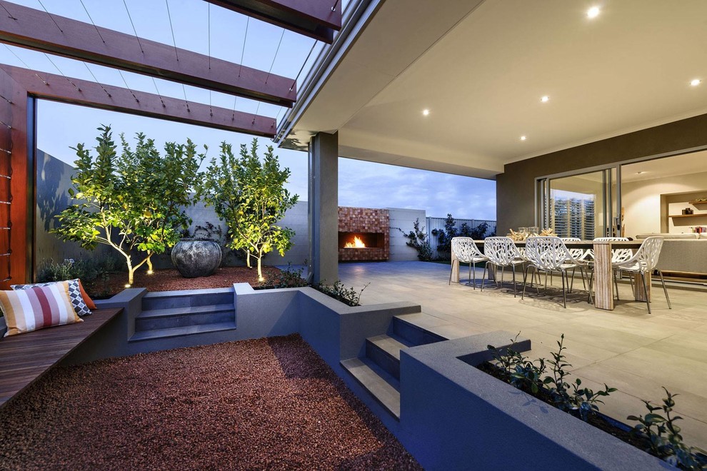 Cette image montre une terrasse design avec une extension de toiture et une cheminée.