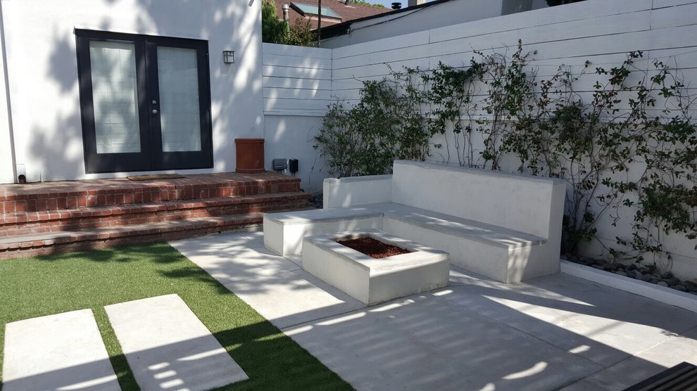 Réalisation d'une petite terrasse arrière minimaliste avec un foyer extérieur, une dalle de béton et un gazebo ou pavillon.