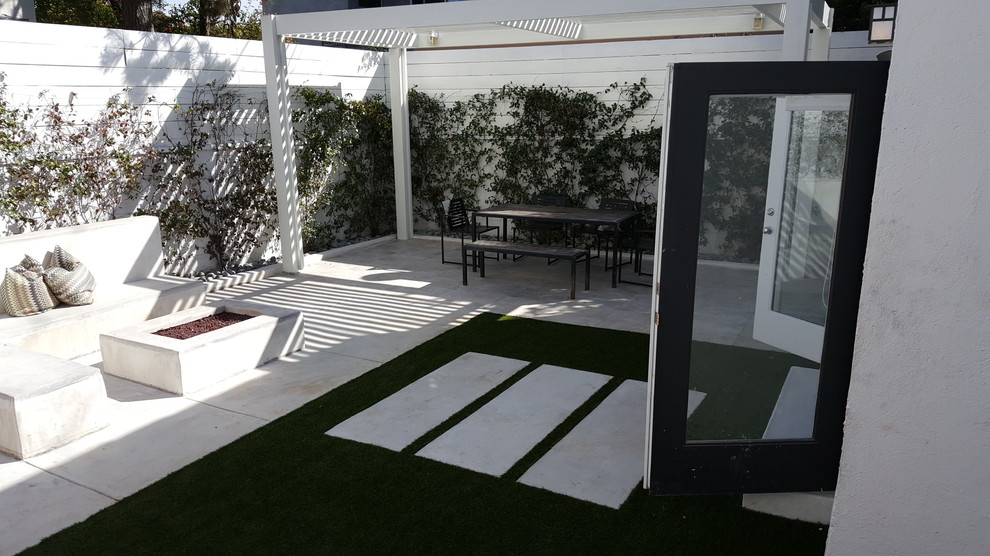 Ejemplo de patio minimalista pequeño en patio trasero con brasero, losas de hormigón y cenador