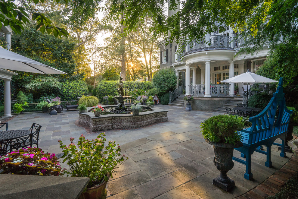 Inspiration for a large timeless backyard stone patio fountain remodel in Other with a roof extension