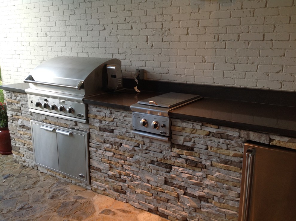 Example of a mid-sized transitional backyard stone patio kitchen design in Dallas with a roof extension