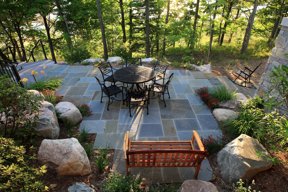 Idée de décoration pour une grande terrasse arrière tradition avec des pavés en pierre naturelle et aucune couverture.