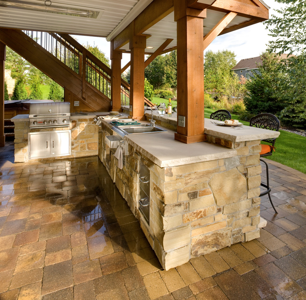 This is an example of a medium sized classic back patio in Minneapolis with an outdoor kitchen, brick paving and a roof extension.