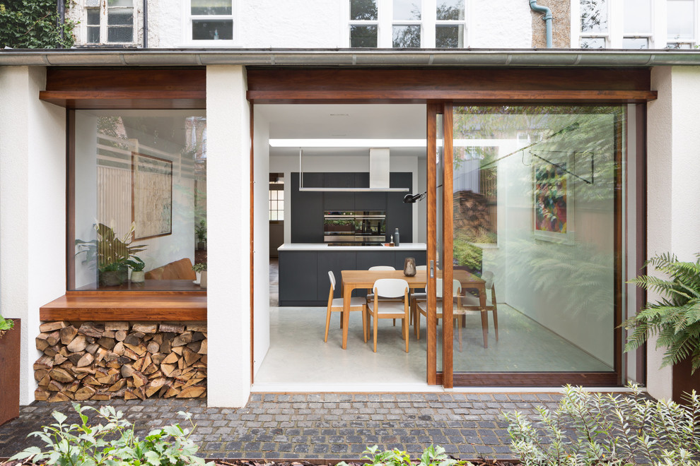 This is an example of a contemporary back patio in London with concrete paving and no cover.