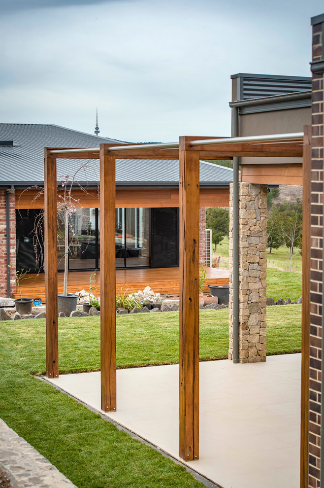 Esempio di un patio o portico minimalista di medie dimensioni e dietro casa con piastrelle e nessuna copertura