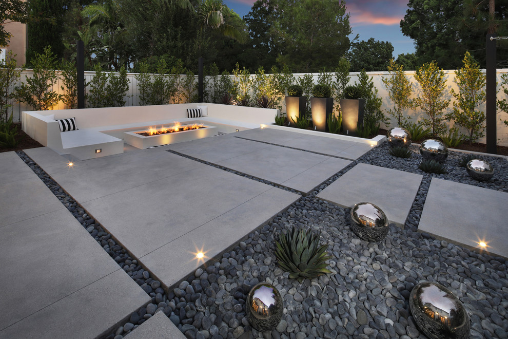 Inspiration pour une grande terrasse arrière minimaliste avec un foyer extérieur, une dalle de béton et un gazebo ou pavillon.