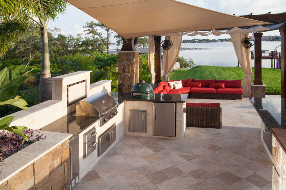 Idée de décoration pour une grande terrasse arrière design avec une cuisine d'été, des pavés en pierre naturelle et une pergola.
