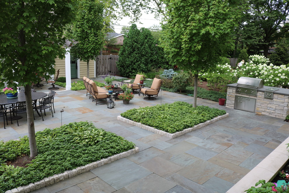 Modelo de patio campestre grande sin cubierta en patio trasero con cocina exterior y adoquines de piedra natural