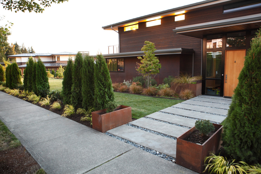 Modelo de patio moderno en patio trasero con fuente, adoquines de hormigón y pérgola
