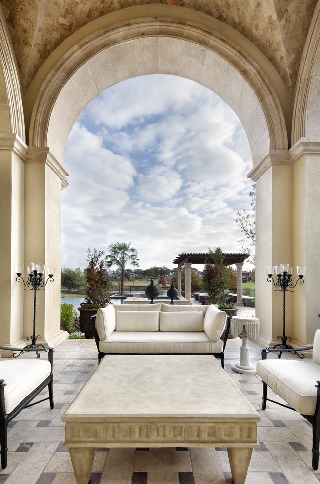 Example of a tuscan patio design in Dallas with a roof extension