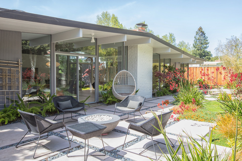 Cette image montre une terrasse arrière vintage avec un foyer extérieur, une dalle de béton et aucune couverture.