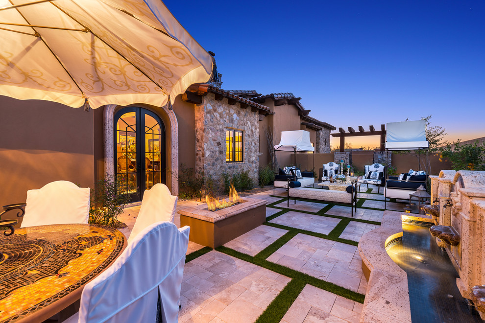 Immagine di un ampio patio o portico mediterraneo dietro casa con un focolare, pavimentazioni in pietra naturale e un tetto a sbalzo