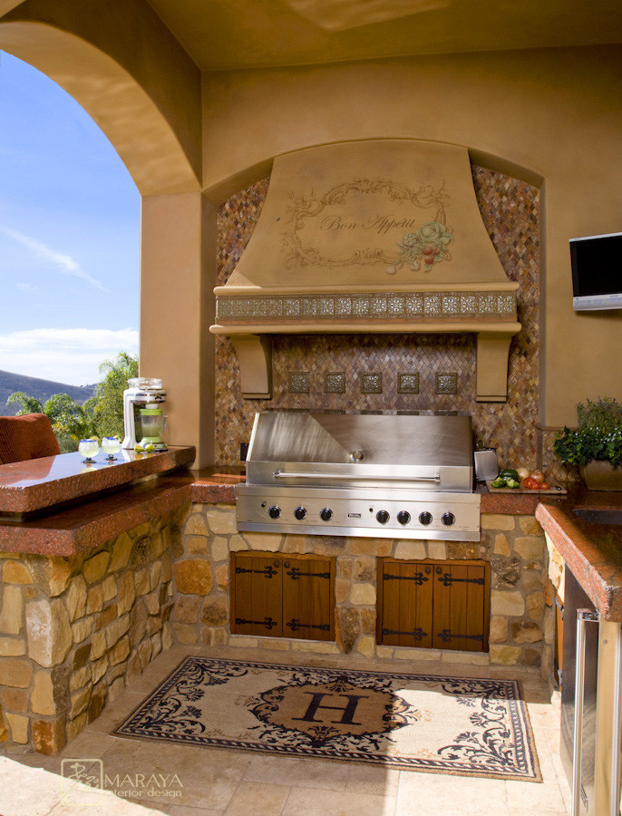 Aménagement d'une terrasse arrière méditerranéenne de taille moyenne avec une cuisine d'été, des pavés en pierre naturelle et une extension de toiture.