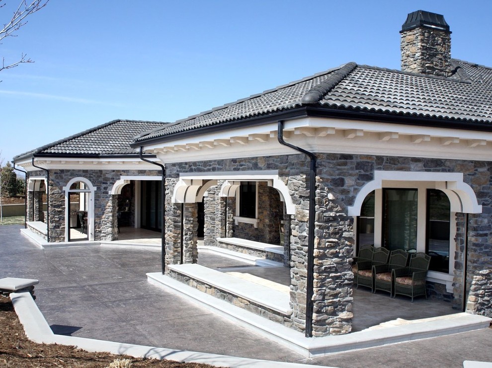Foto di un ampio patio o portico mediterraneo dietro casa con lastre di cemento e un tetto a sbalzo