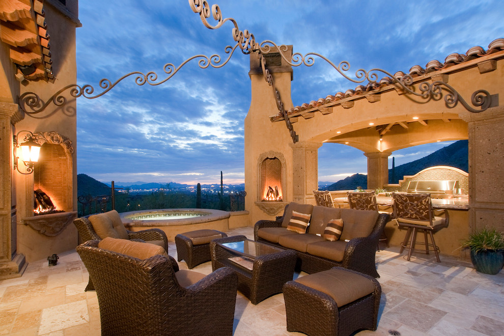 This is an example of an expansive mediterranean back patio in Phoenix with a fire feature, natural stone paving and a gazebo.