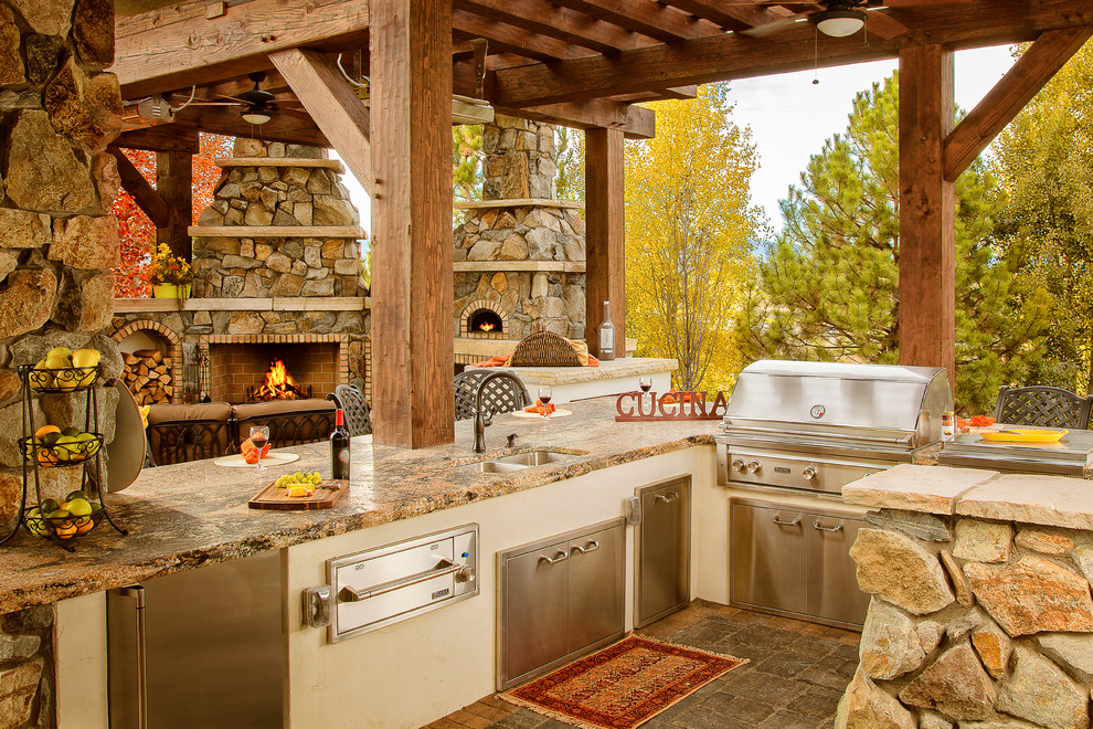 Cette image montre une grande terrasse arrière chalet avec une cuisine d'été, des pavés en béton et une pergola.
