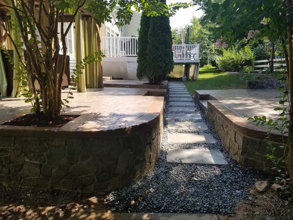 Großer Patio hinter dem Haus mit Kübelpflanzen, Stempelbeton und Gazebo in Sonstige