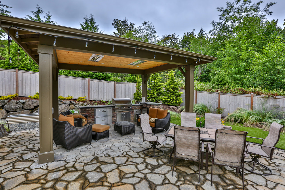 Large modern back patio in Seattle with an outdoor kitchen, natural stone paving and a gazebo.